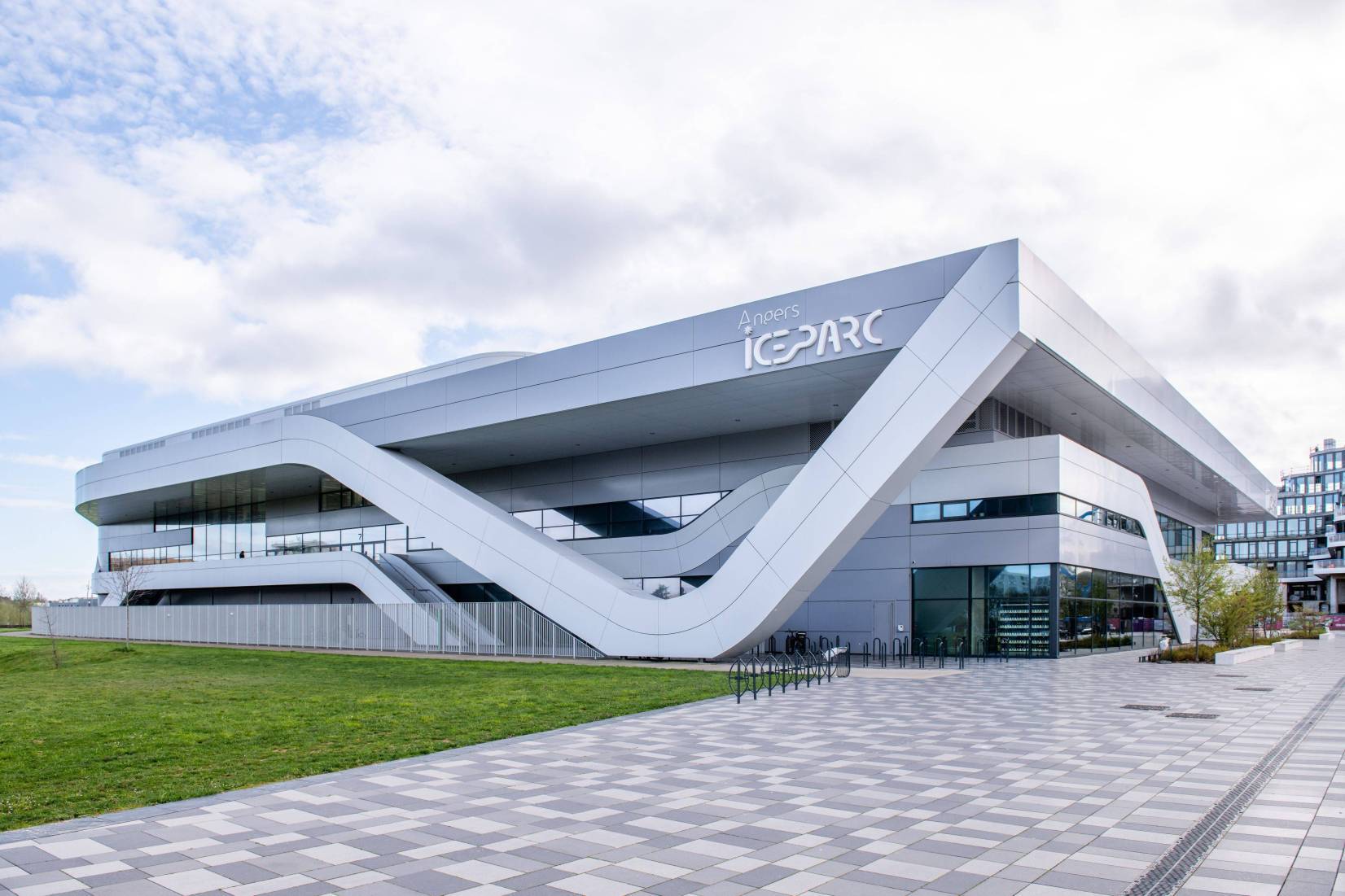 La façade blanche et anguleuse d'Angers ICEPARC, vue de l'extérieur, avec le nom de la patinoire en grandes lettres sur le bâtiment