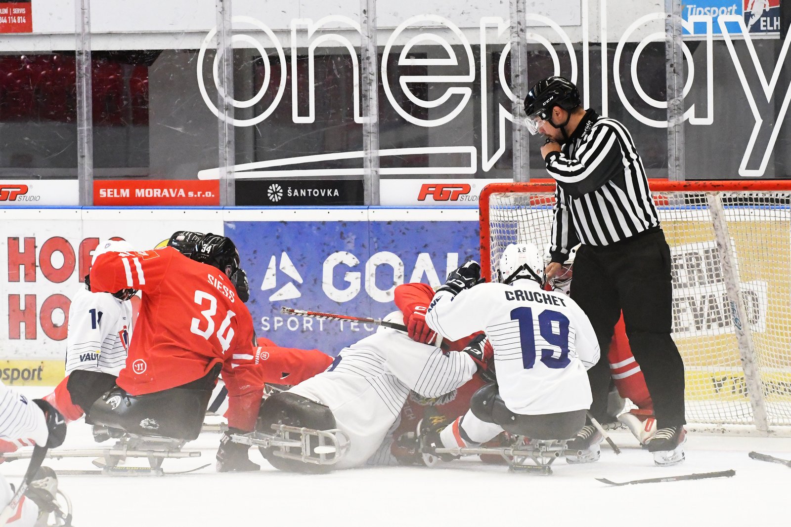 L'altercation devant le but : l'Autrichien Siess, numéro 34 en maillot rouge, aux prises avec des joueurs français en blanc dont Cruchet, numéro 19, luges emmêlées sur la glace, pendant que l'arbitre se penche sur la mêlée