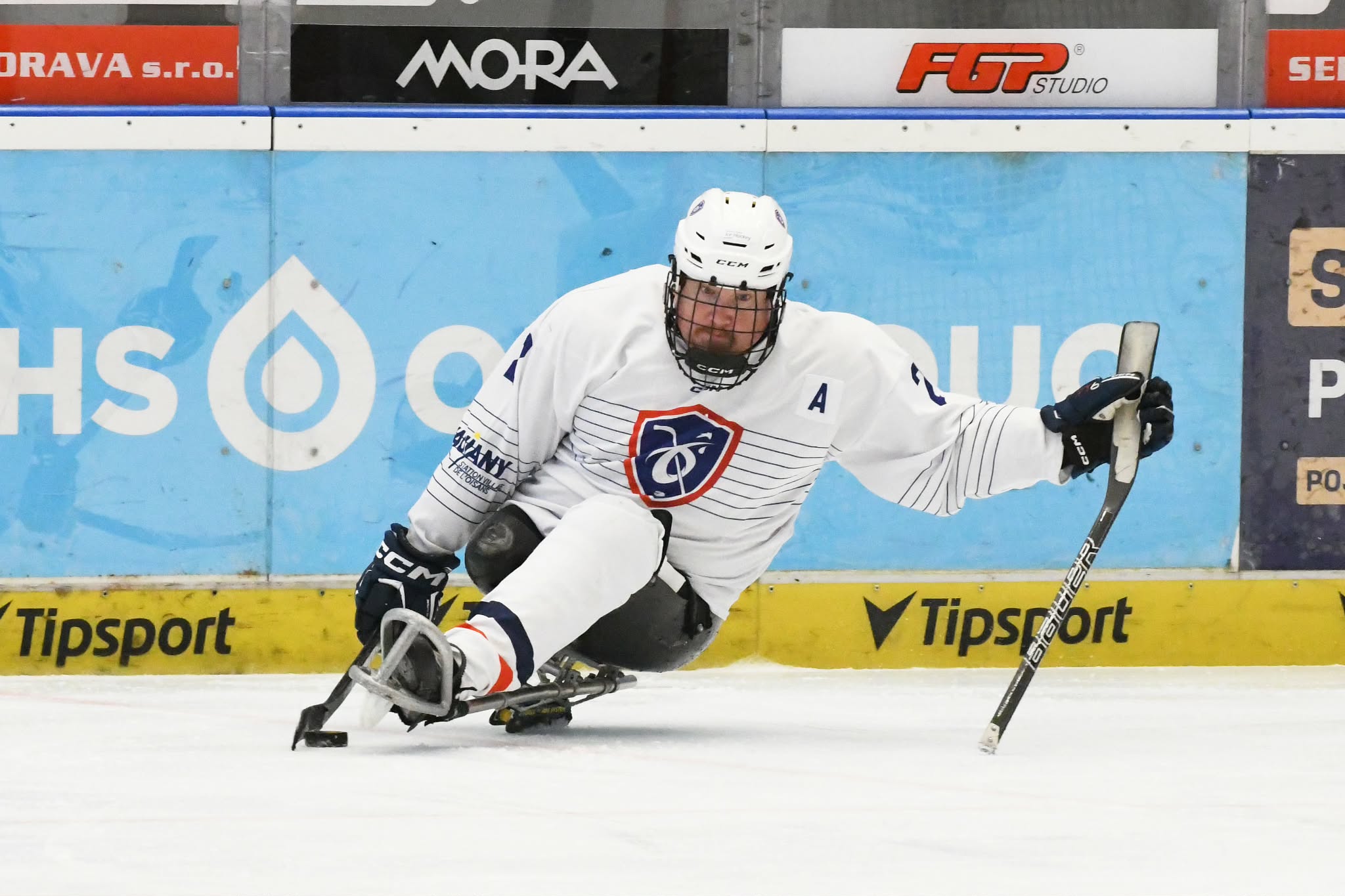 Sur ma luge en maillot blanc de l'équipe de France, le A d'assistant capitaine sur la poitrine, penché le long de la bande pour pousser le palet du bout de ma crosse